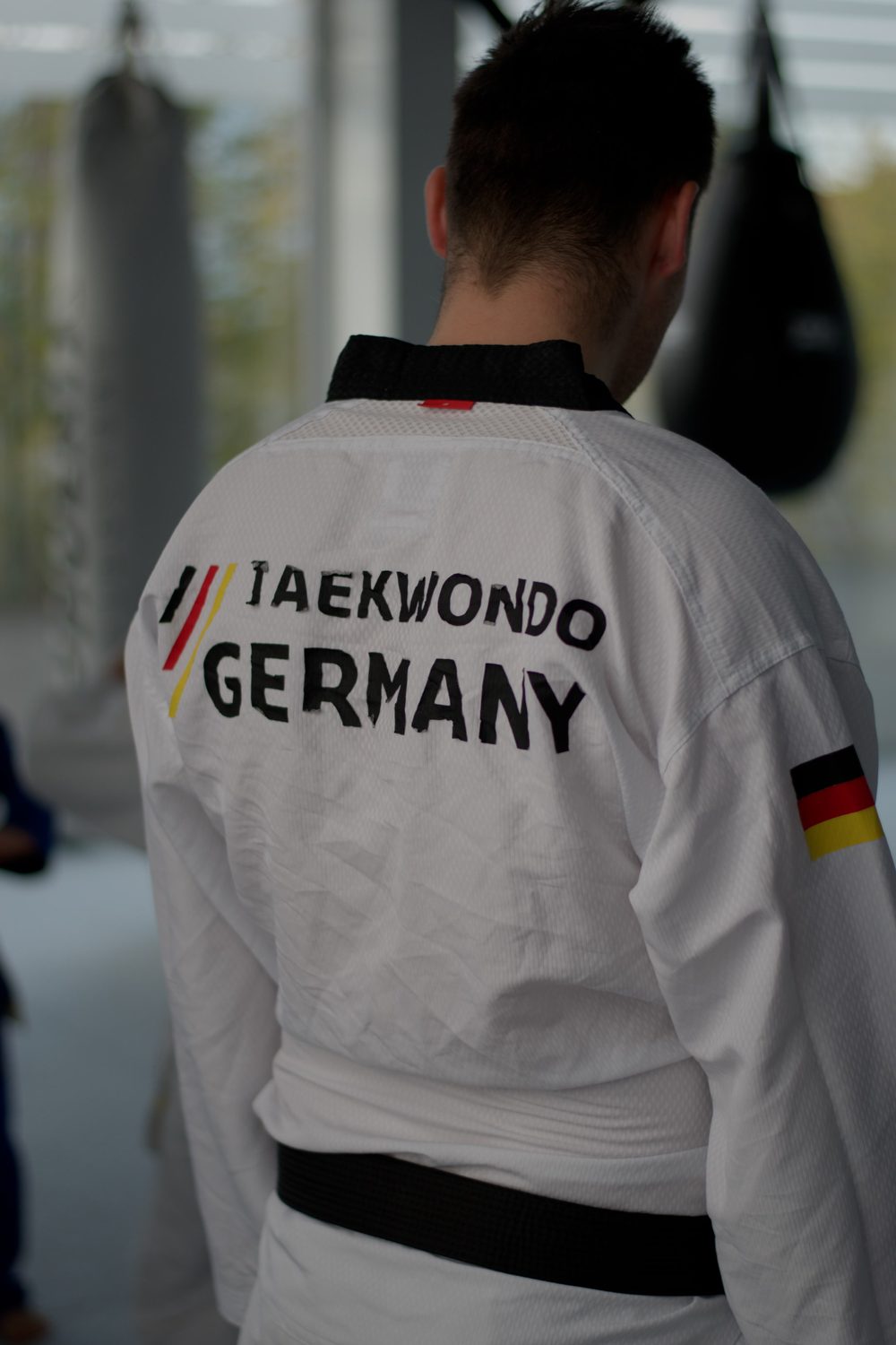 Taekwondo-Sportler mit schwarzem Gürtel, Rückenaufdruck „Taekwondo Germany“