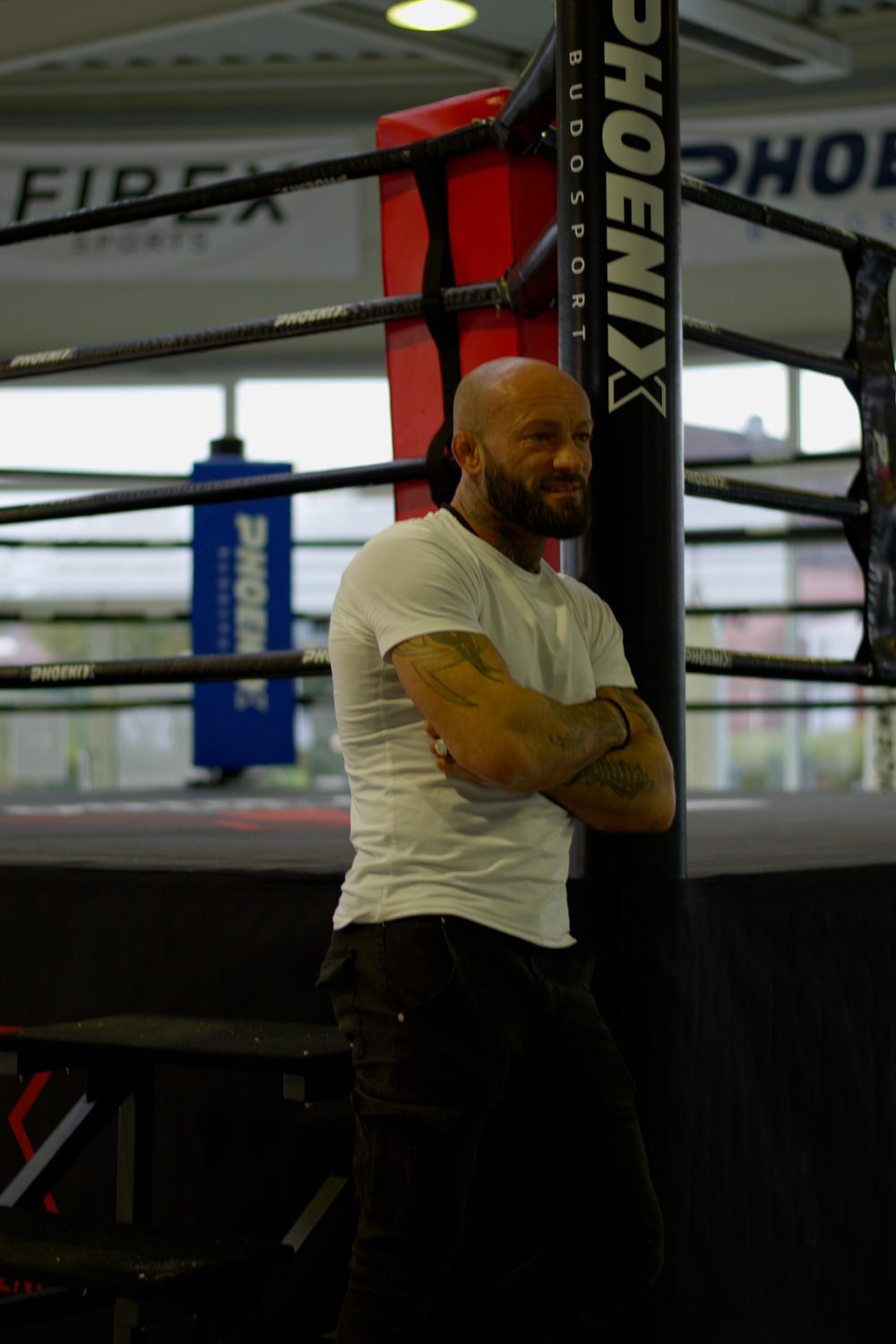 Viktor Kessler lehnt lächelnd mit verschränkten Armen am Ringpfosten in seinem Gym in Warendorf